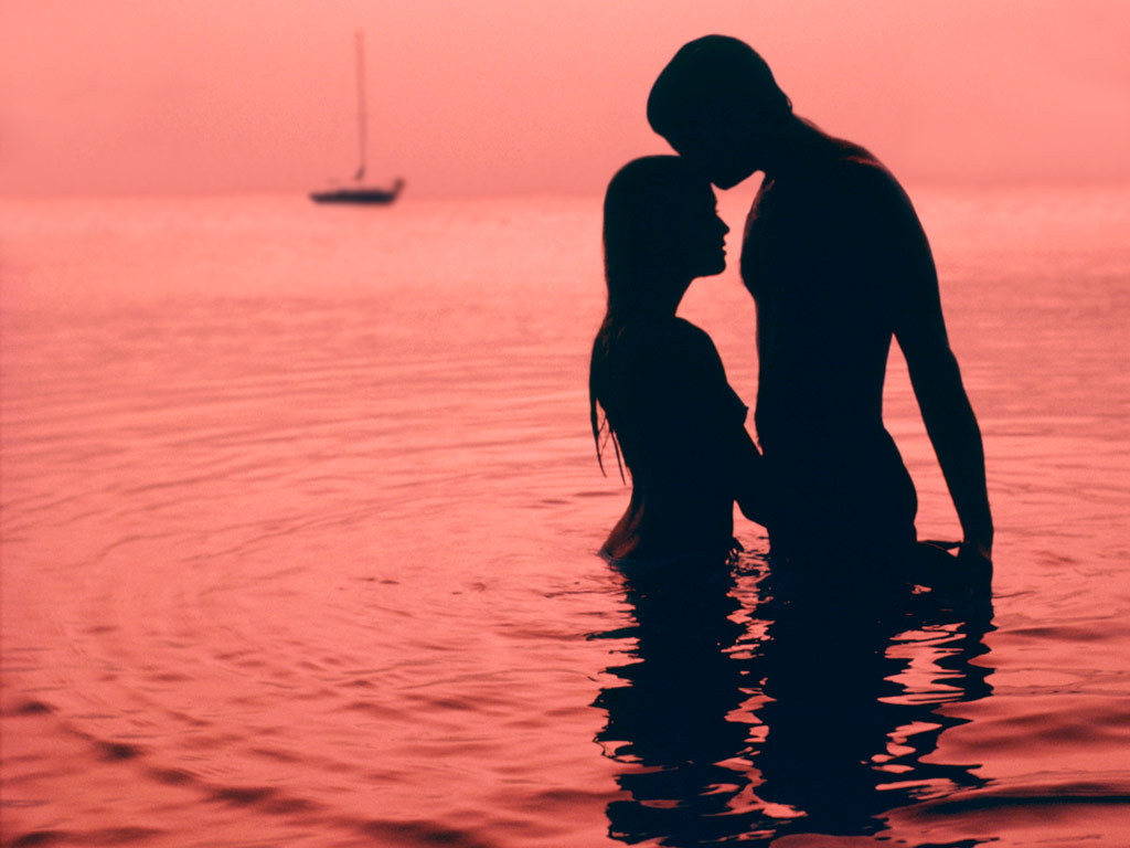 Young nude couple passionately embracing before making love in the water